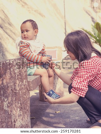 mother wearing shoe to baby in the park