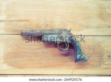 Old short gun on the wooden board , rusty hand gun