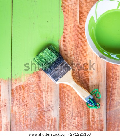 Paint brush and color bowl on wood board, brush and bowl with green coating color