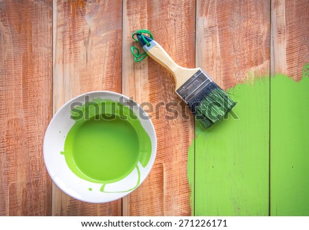 Paint brush and color bowl on wood board, brush and bowl with green coating color