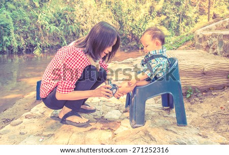 Mother wearing shoe to baby at outdoor park