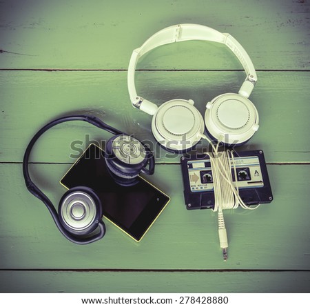 Concept of different technology between Smartphone cassette tape and headphone all were on the wood board