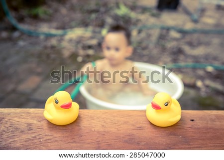 yellow duck on wood board  with blurred  baby bathing background