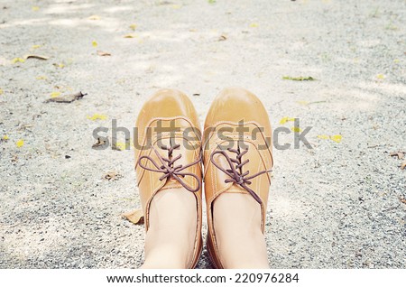 Close up of female\'s feet wear the leather brown shoes sitting in the garden. Relaxing in Abstract meaning. Vintage look.