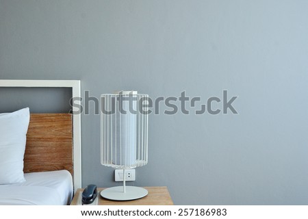 Bed with white linen beside night table with lamp. Minimalism interior.