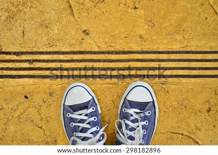 Blue Sneaker shoes standing on yellow street. Canvas shoes on street. Top view.