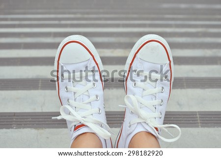 White Sneaker shoes sitting on street. Canvas shoes. Pale tone.