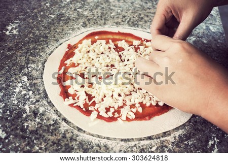 Woman making pizza on table. Close up. Toned image.