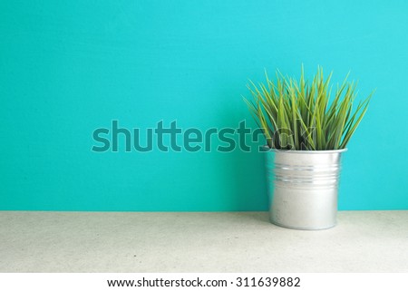 Green grass plant in vintage pot on table  front mint green background. Interior Decorating Item. Vintage effect.