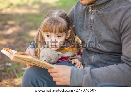 Daddy daughter reading a book outdoor