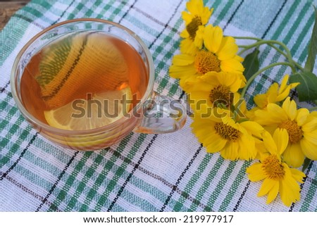 Tea in a glass cup with lemon and yellow flowers