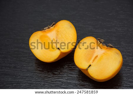 Fresh persimmon slide on black wood black ground