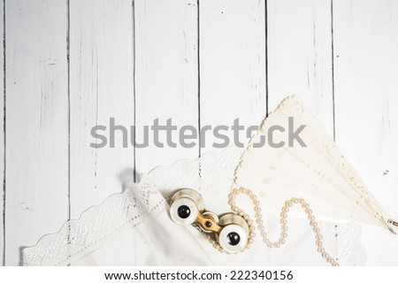 Vintage classic composition with antique binoculars, pearl beads, ivory fan and cotton white napkin a white wooden background shabby chic style dance theme
