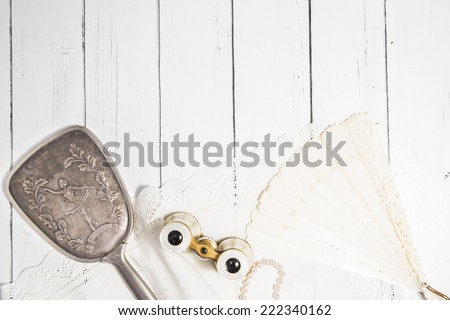 Vintage classic composition with antique binoculars, pearl beads, ivory fan and cotton white napkin a white wooden background shabby chic style dance theme