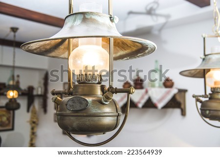 Old retro vintage metallic decorative lamp with patina hanging on the ceiling of a russian tavern interior. Rustic style electric lamp imitated antique rustic kerosene lamp