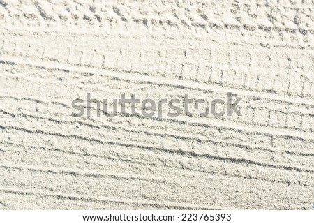 Ribbed tyre traces on grey silver dry sand. Background for articles about traveling, transport and ecology