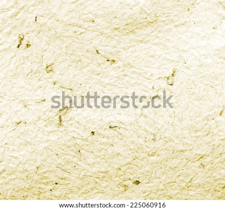Homemade hand crafted textured paper with inclusions of gold foil and floral petals on a yellow background. Useful for scrapbooking and greeting cards