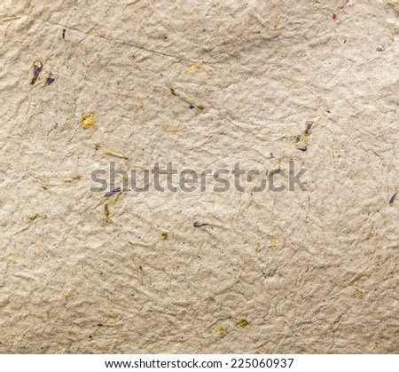 Homemade hand crafted textured paper with inclusions of gold foil and floral petals on a brown beige background. Useful for scrapbooking and greeting cards