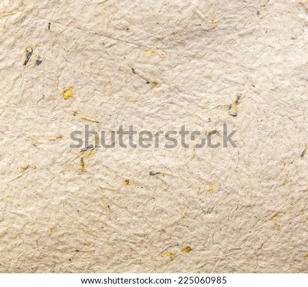 Homemade hand crafted textured paper with inclusions of gold foil and floral petals on a beige background. Useful for scrapbooking and greeting cards