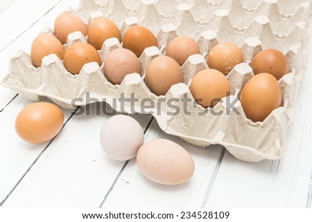 Fresh ginger eggs packed in a gray ecological paper container on a white wooden table background