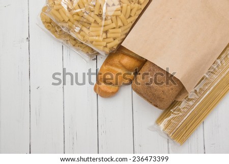 Loaf of grey wheat rye bread in a craft paper packing on a white wooden background