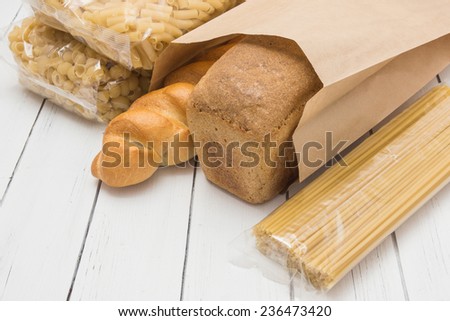 Loaf of grey wheat rye bread in a craft paper packing on a white wooden background