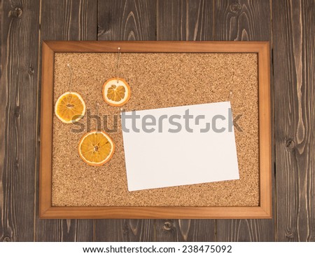 ?ork Pin board with blank sheet of paper and christmas tree toys on little pins hanging on a dark wooden background