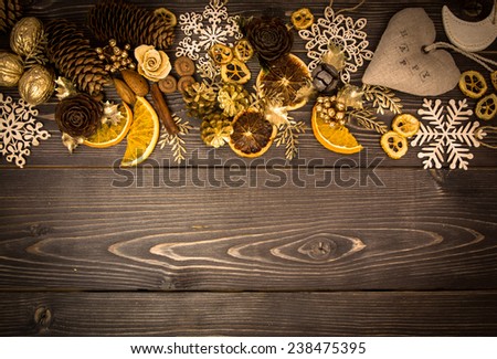 Christmas and new year winter cozy border with dry spices, fir cones and other decor on a dark wooden background.