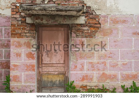 Porch with a wooden door with old rough antique block wall colored pink brick with cracks and splits