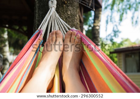Woman legs in a colorful linen hammock in the forest