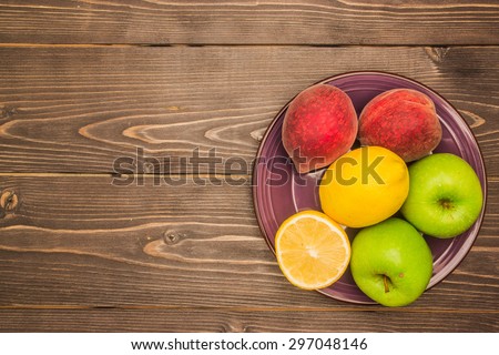 Fruits on a ceramic violet dish isolated on a dark wooden background