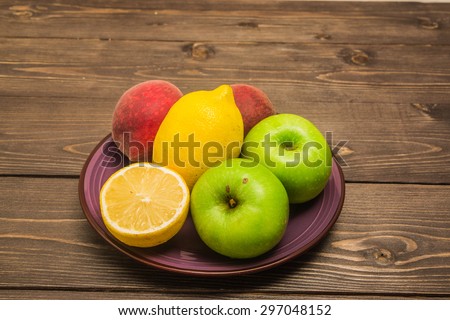 Fruits on a ceramic violet dish isolated on a dark wooden background