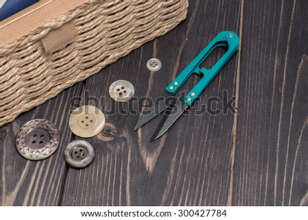 Braided sewing box with tools and buttons on a dark wooden table