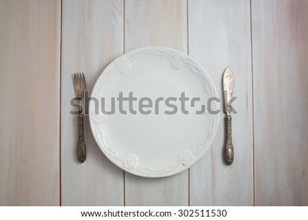 Served table with an antique table, silver folk and knife on a white wooden table