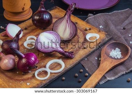 Cutted onion on a wooden board with salt and pepper in a wooden spoons. Still life for a food blog
