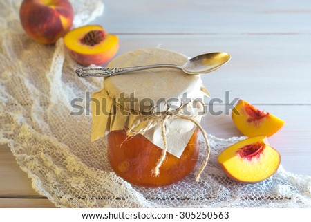 Bright juicy apricot jam in a glass jar with peaches, spoon and napkin