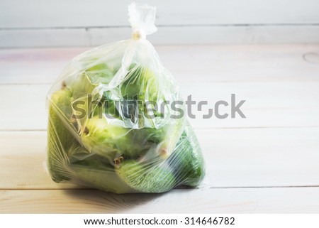 Fresh green cucumbers in a plastic package on a white wooden table
