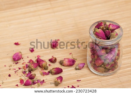 Dried roses, wooden scoop of rose tea on bamboo mat