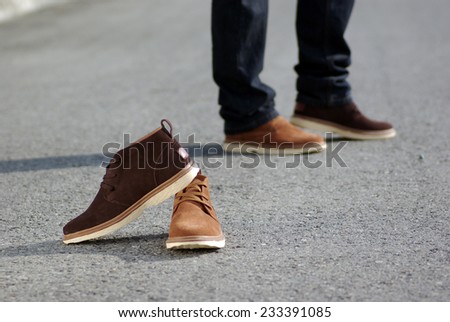 Human foot with brown leather shoes and jeans