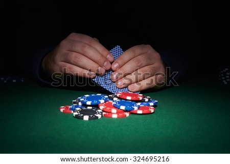 Poker chips on table with hands and cards in casino with black background