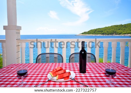 View of sea and blue sky from terrace in Hvar, Croatia. Chilled watermelon and black wine with two wineglass on the table.