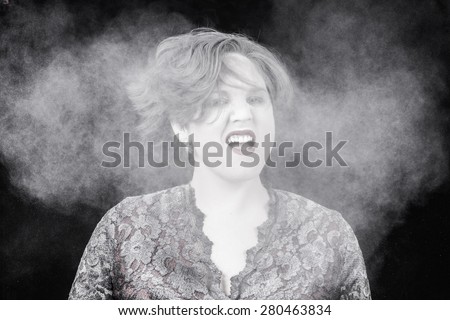 A woman making a crazy facial expression while shaking powder out of her hair. Her mouth open. Powder exploding everywhere.