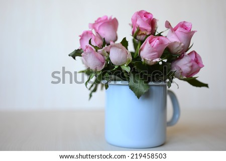 Roses. A small bouquet of winter roses in a enameled light blue kettle on a light background.