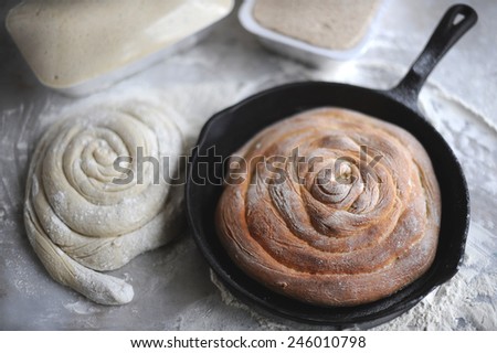 Home cooked bread in cast iron pan. Dough bread aside packed and spiral dough bread ready for cooking on a marble background.