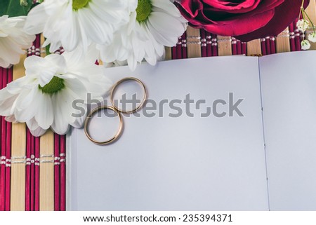 open notepad with wedding rings on a background of flowers