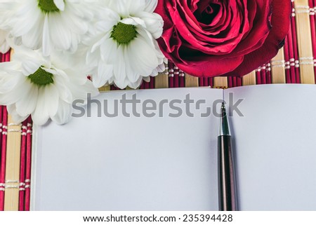 open notepad with pen on a background of flowers