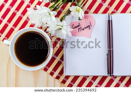 open notepad, cup of coffee and flower on striped napkin