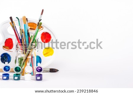 isolated paint palette and paints brushes in glass
