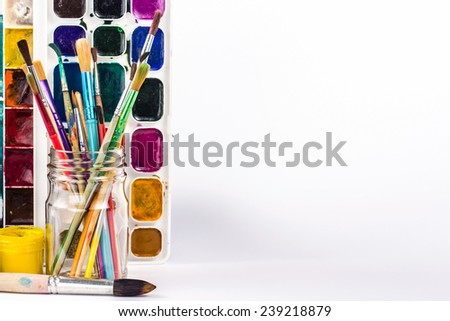 isolated paints brushes in glass and paint palette
