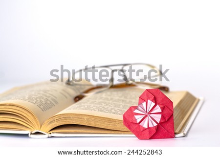 red origami paper heart over open book